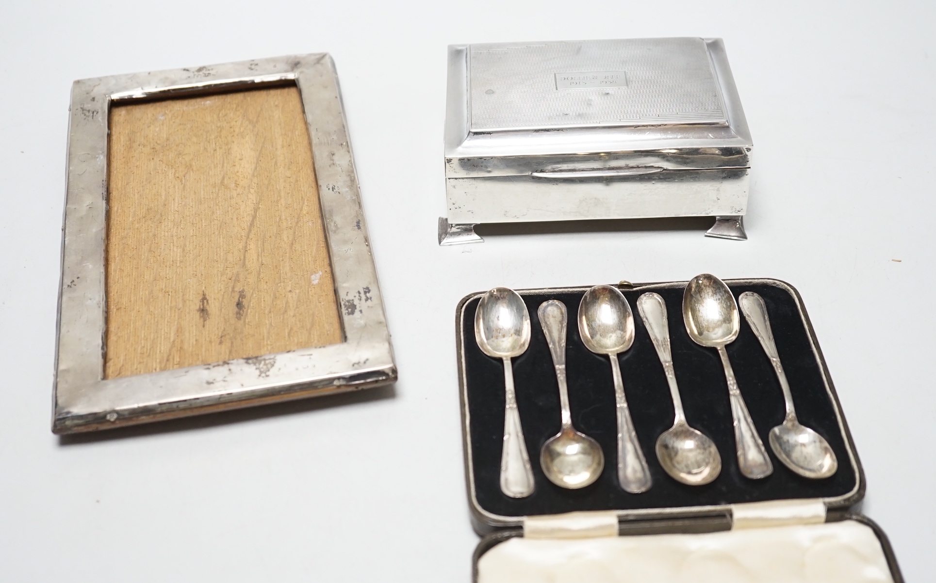 A set of six George VI silver teaspoons, Birmingham, 1939, cased, a silver cigarette box and a silver framed photograph frame.